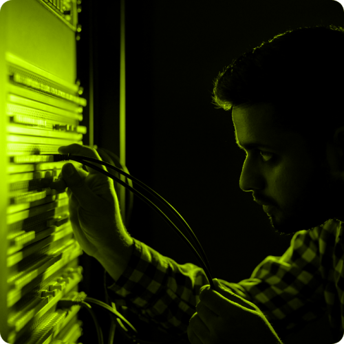 Technician connecting fibre optic cables in a server room.